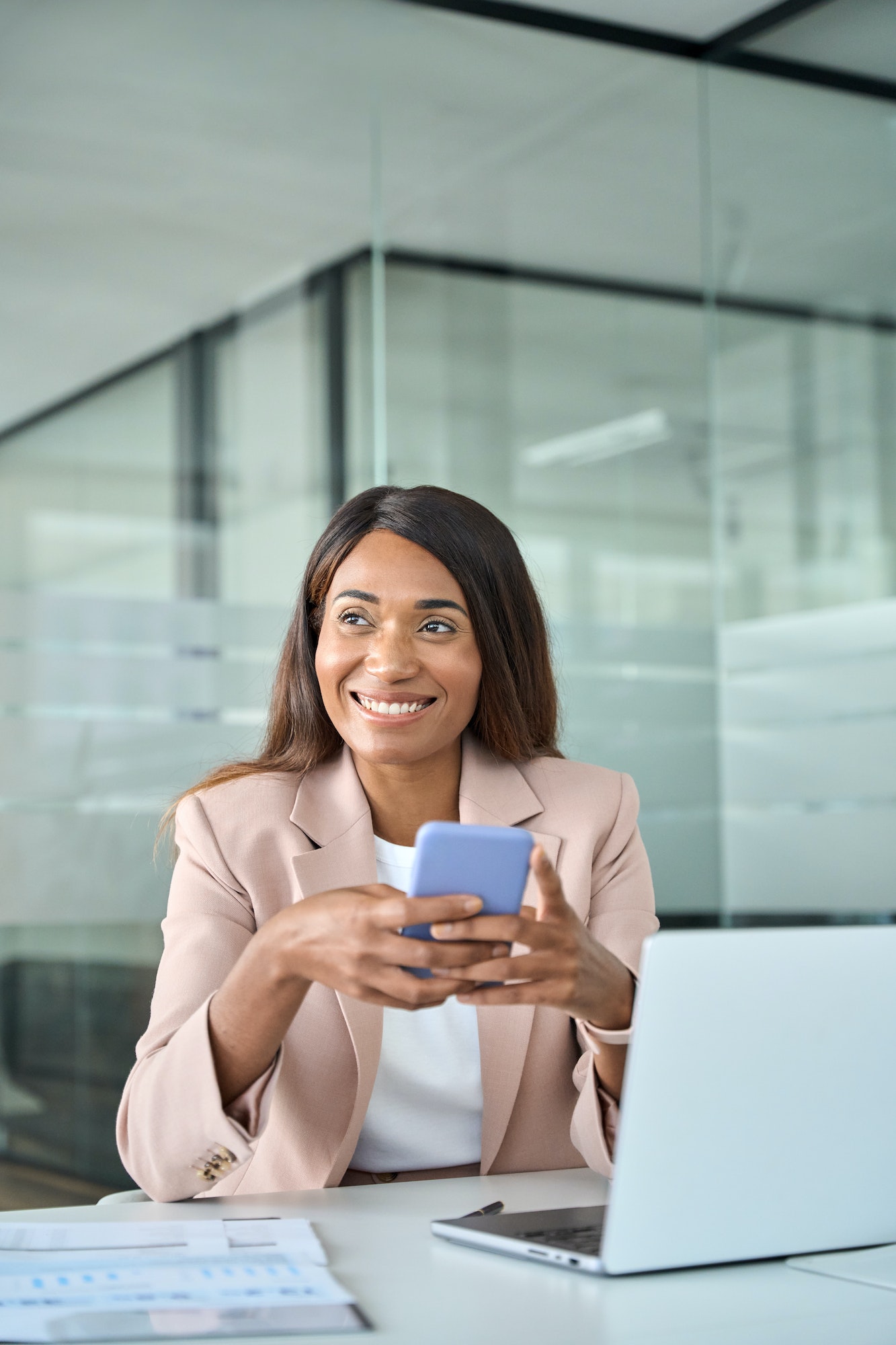 Happy professional African American business woman using phone in office.