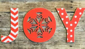 Minimalist holiday decor, the word joy in red and white on a rustic wooden background