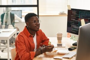 Young African American IT engineer looking at computer screen by lunch