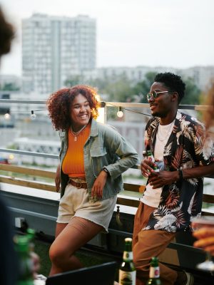 Happy young black couple chatting at party on terrace of rooftop cafe